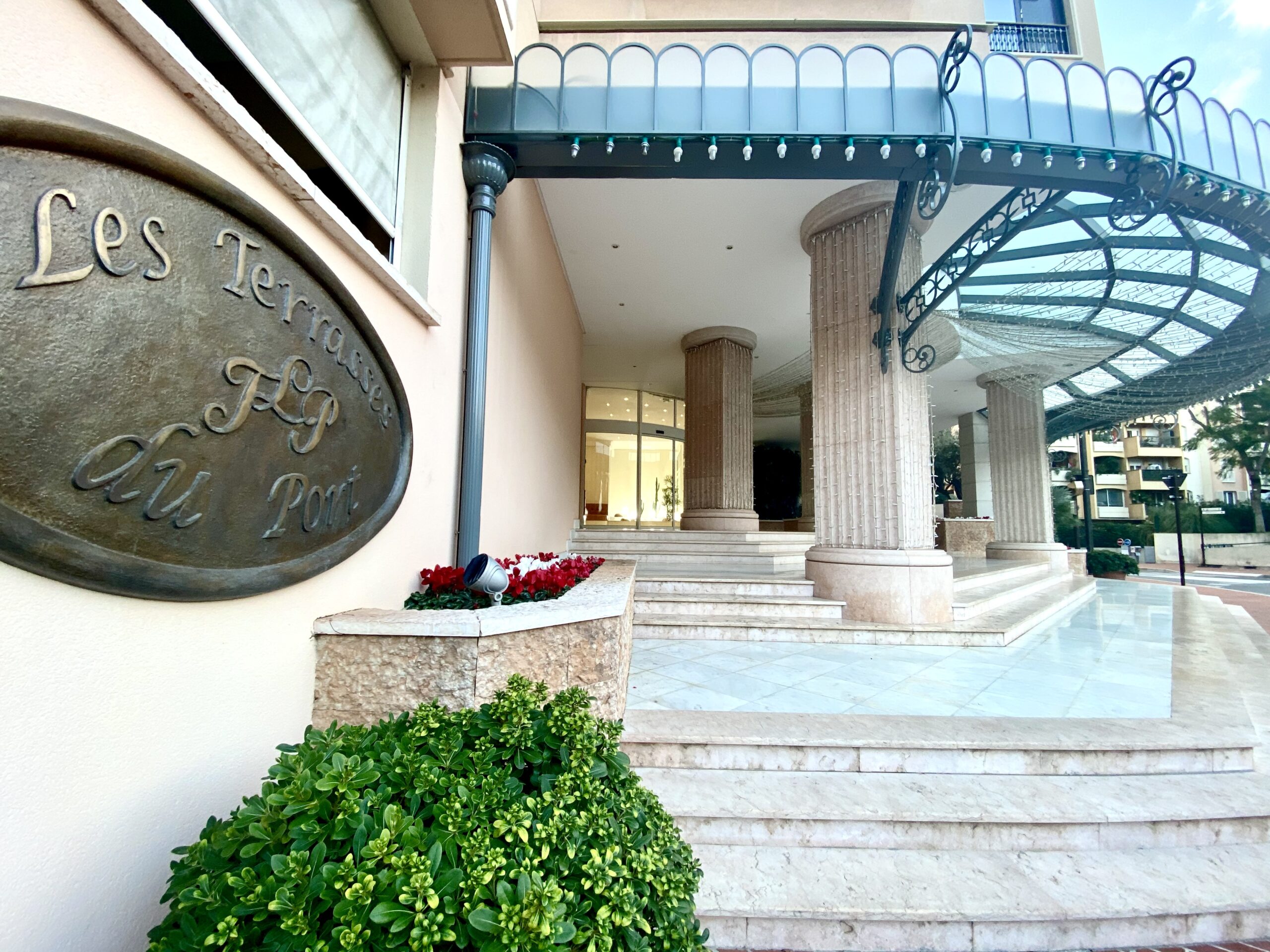Entrance to Les Terrasses du Port Monaco with stone columns and wrought iron canopy