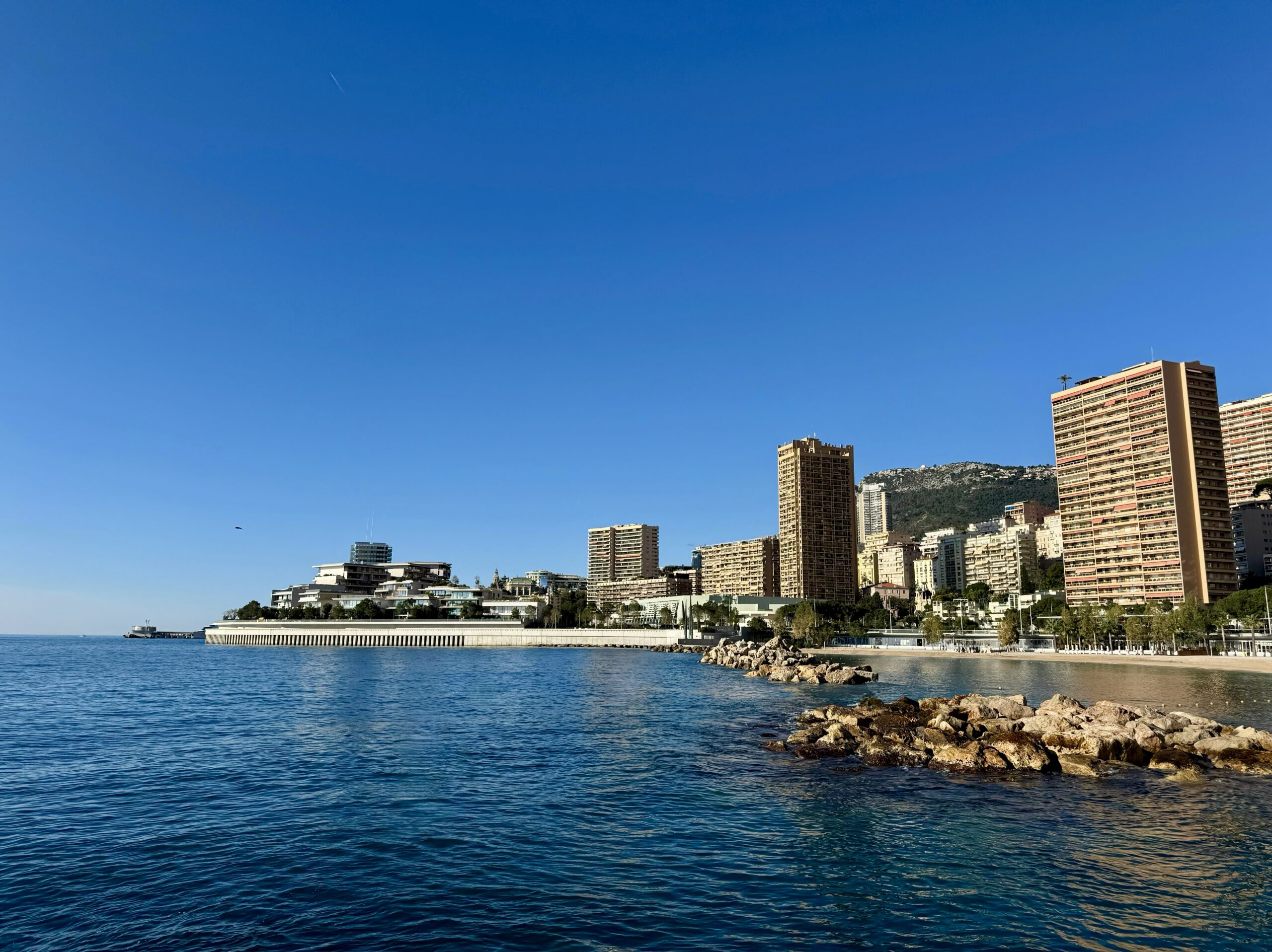 Larvotto beach and seafront skyline with luxury residential towers in Monaco, prime coastal real estate district on the French Riviera